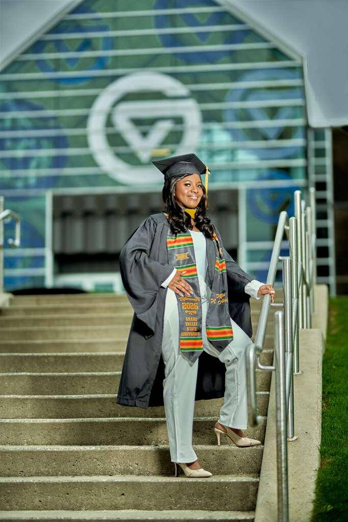 student standing on stairs in graduation regalia